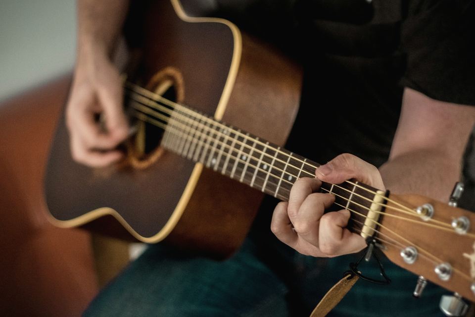 Mains jouant un accord sur une guitare acoustique