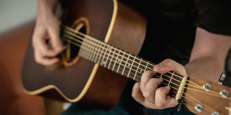 Mains jouant un accord sur une guitare acoustique